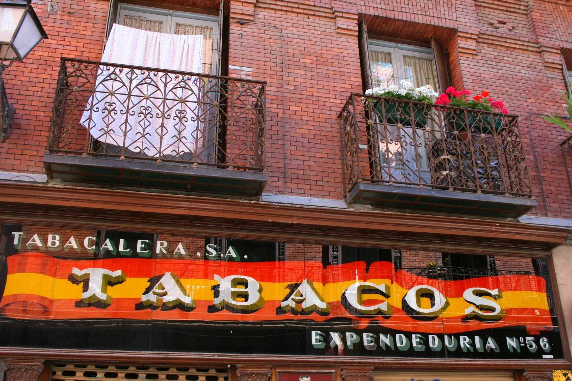 Rótulo clásico de un estanco español con la palabra Tabacos en letras amarillas sobre franjas rojas, bajo dos balcones