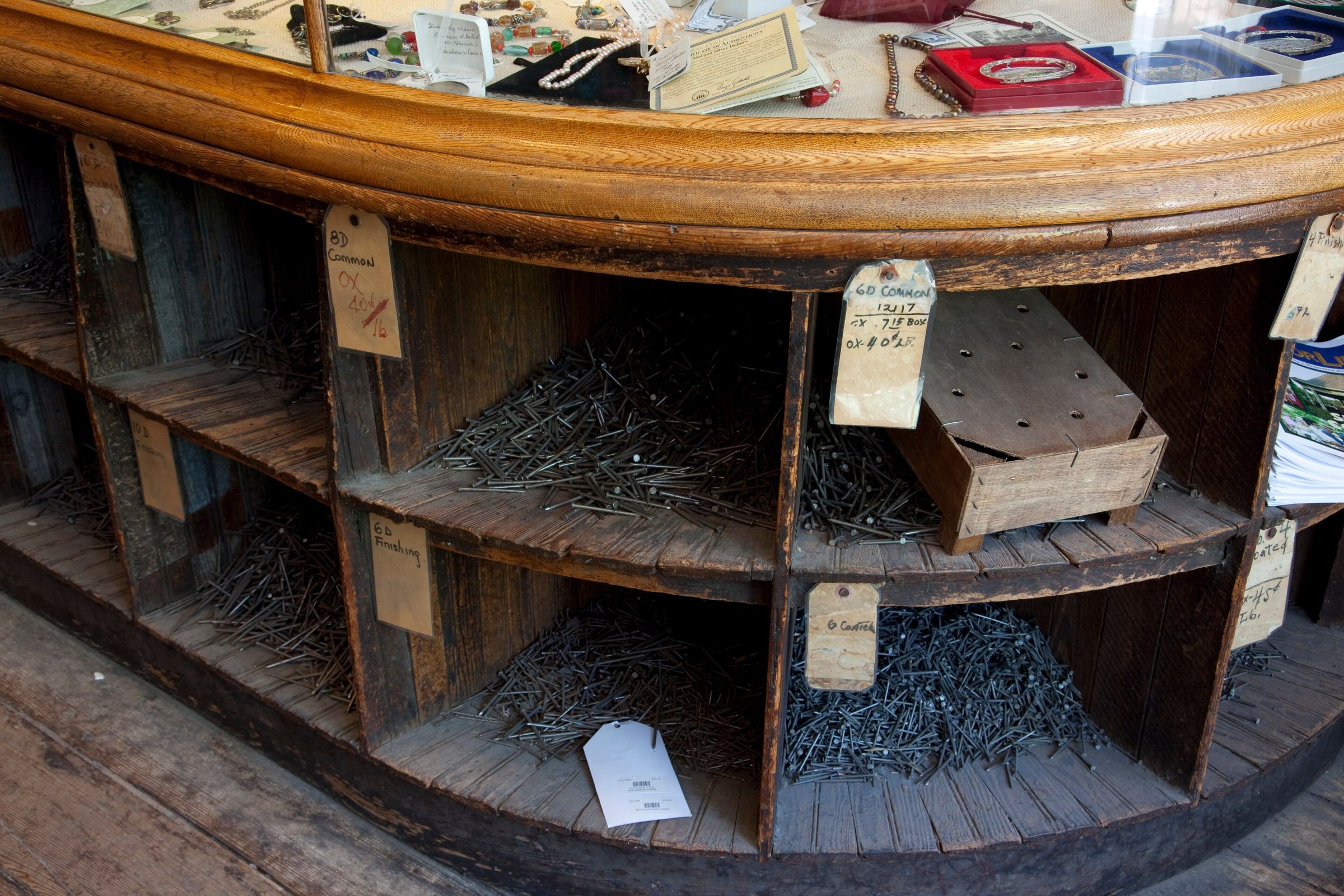 Mostrador curvo de madera de una ferretería antigua con casilleros llenos de clavos y tornillos a granel