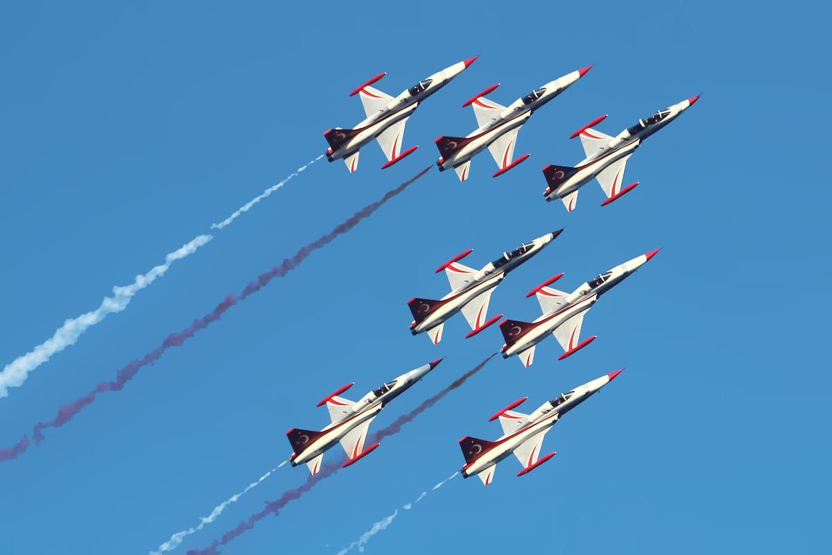 Patrulla de aviones militares volando en formación durante el Festival Aéreo de Torre del Mar, dejando estelas de humo en el cielo azul