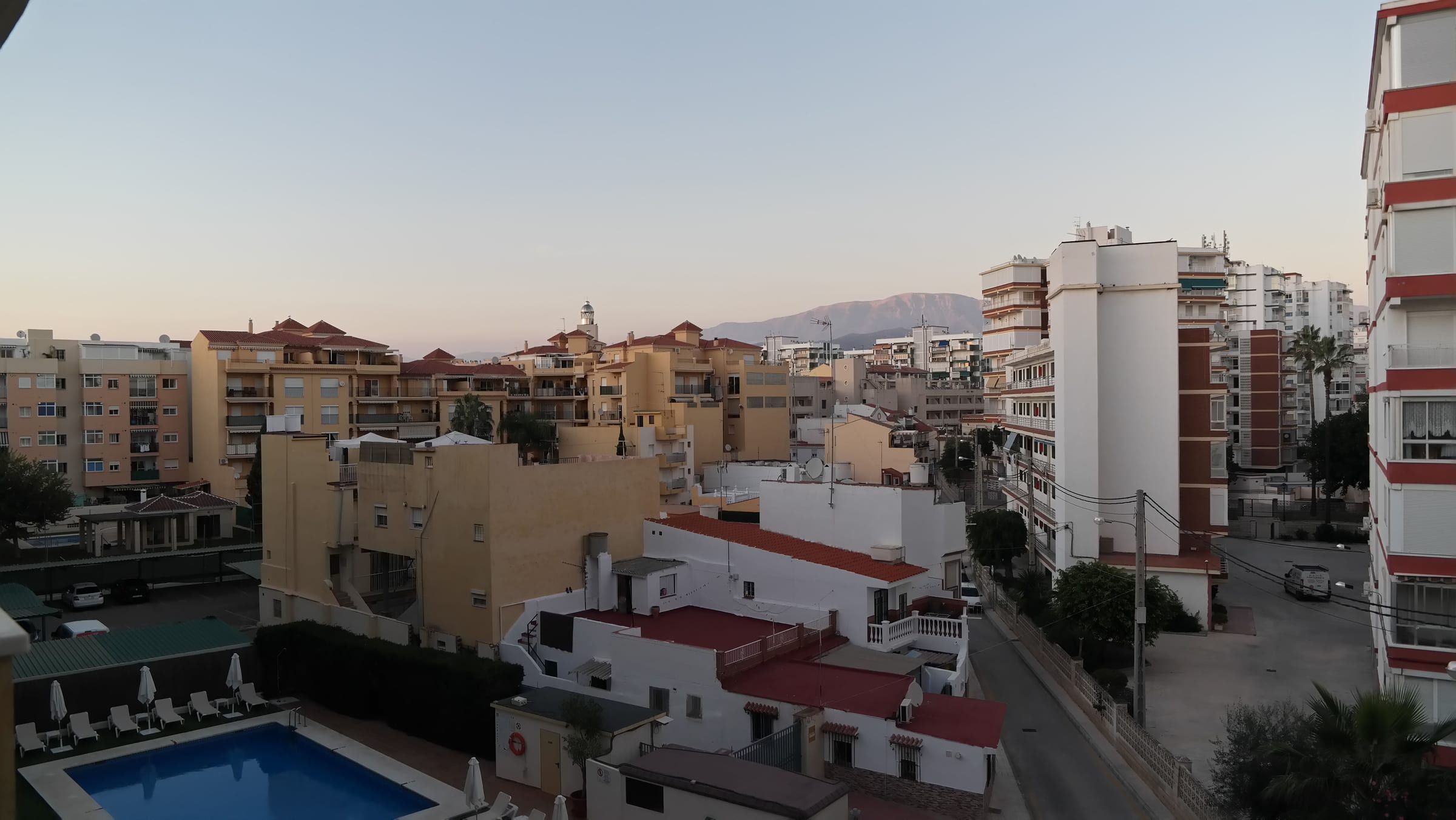 Vista de los tejados y edificios de Torre del Mar al atardecer, con la montaña de la Axarquía al fondo