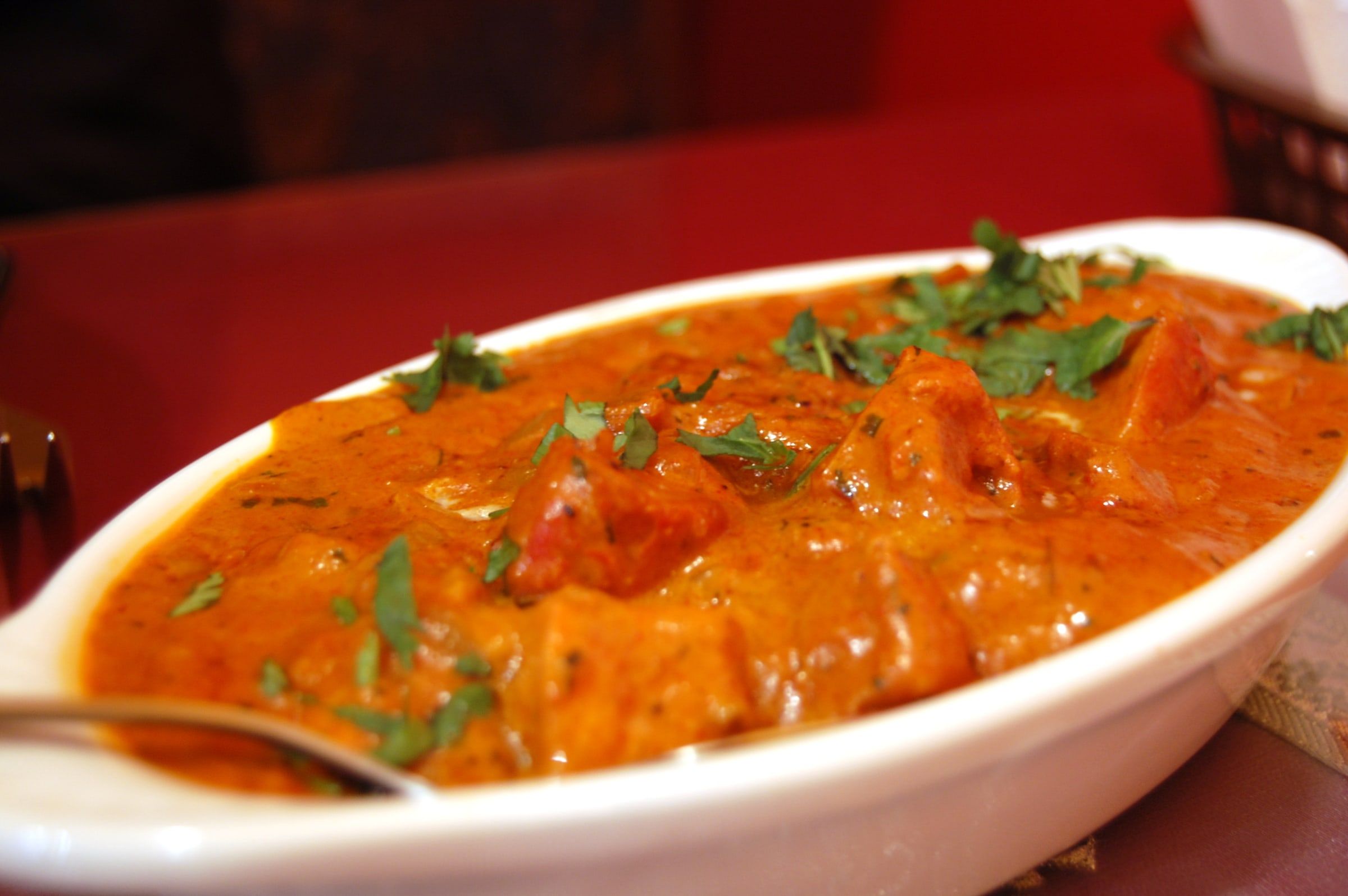 Fuente de pollo a la mantequilla de cocina india, con salsa anaranjada de tomate y nata y cilantro picado por encima