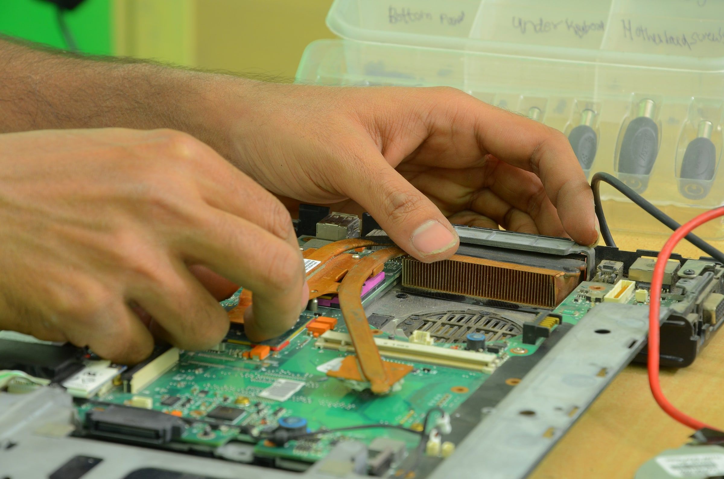 Técnico reparando un ordenador abierto sobre la mesa de trabajo, con la placa base y los componentes a la vista