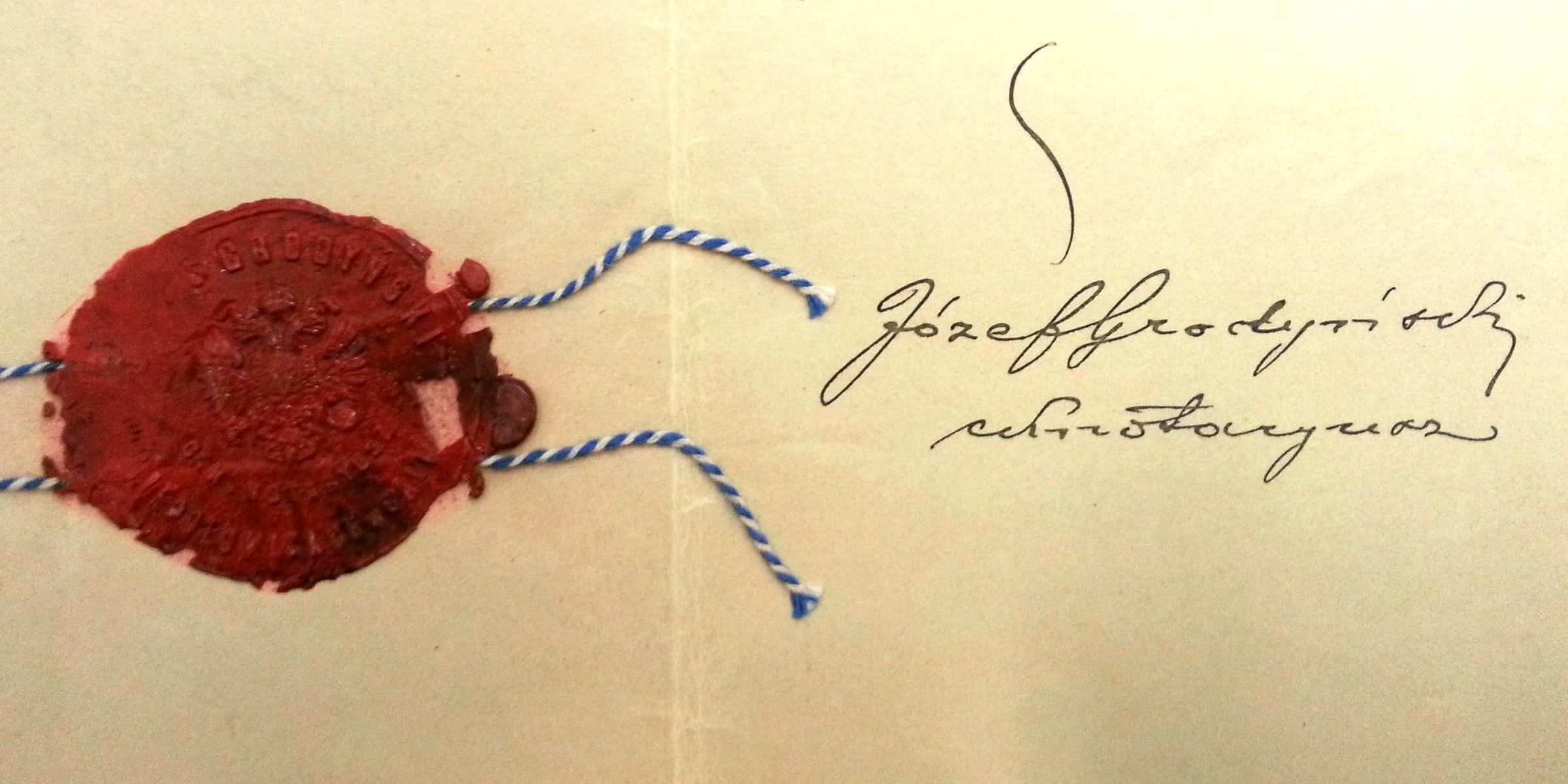 Documento antiguo firmado a mano y cerrado con un sello de lacre rojo y cordón azul y blanco